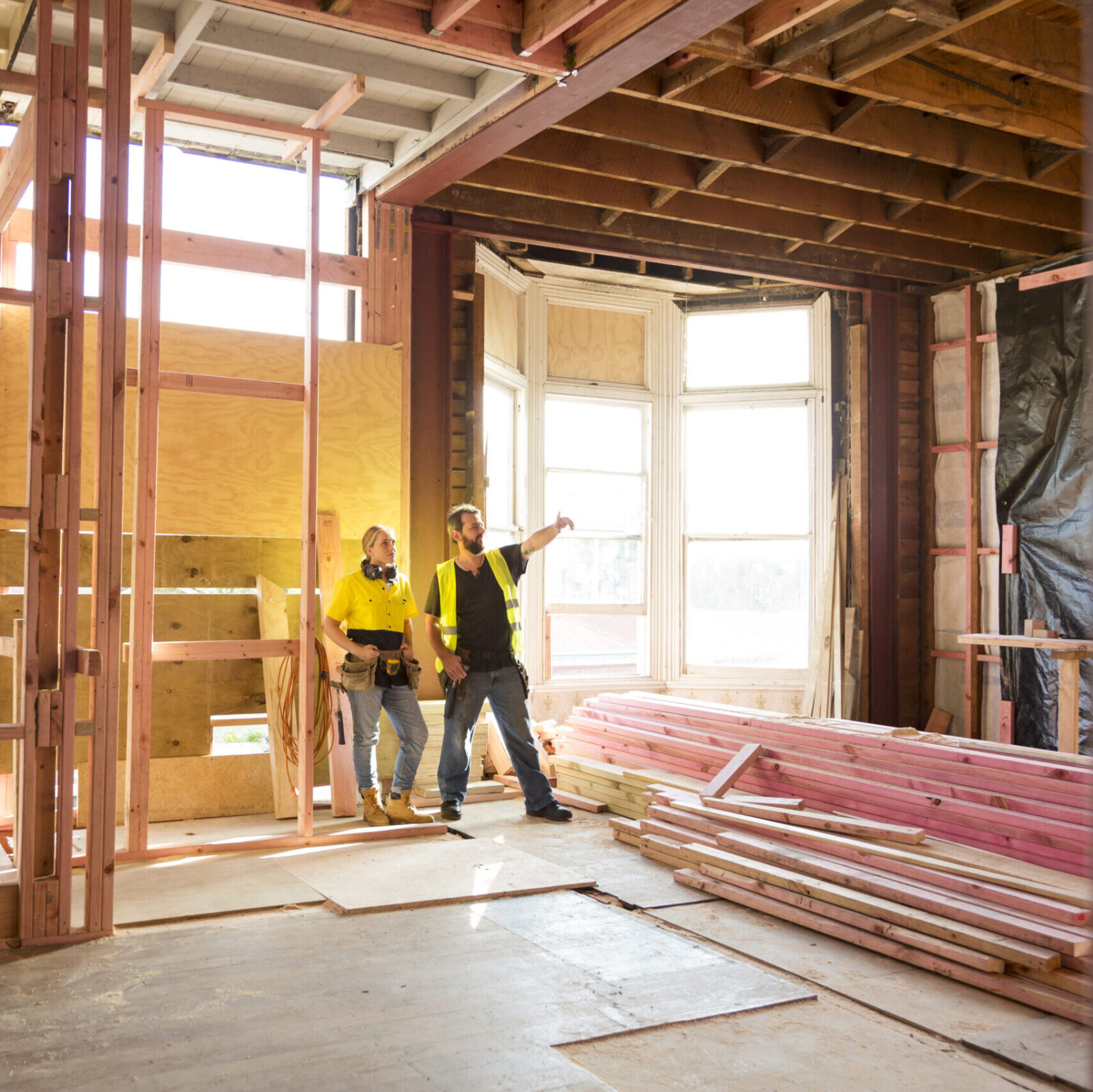 Two construction workers talk together inside large house under renovation